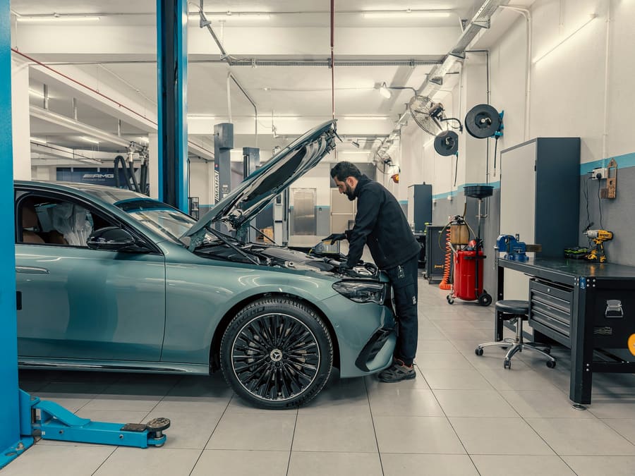 A technician checking under the bonnet of a car in a clean, bright garage workshop